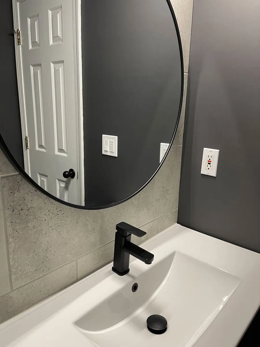 Modern bathroom with round mirror and black faucet
